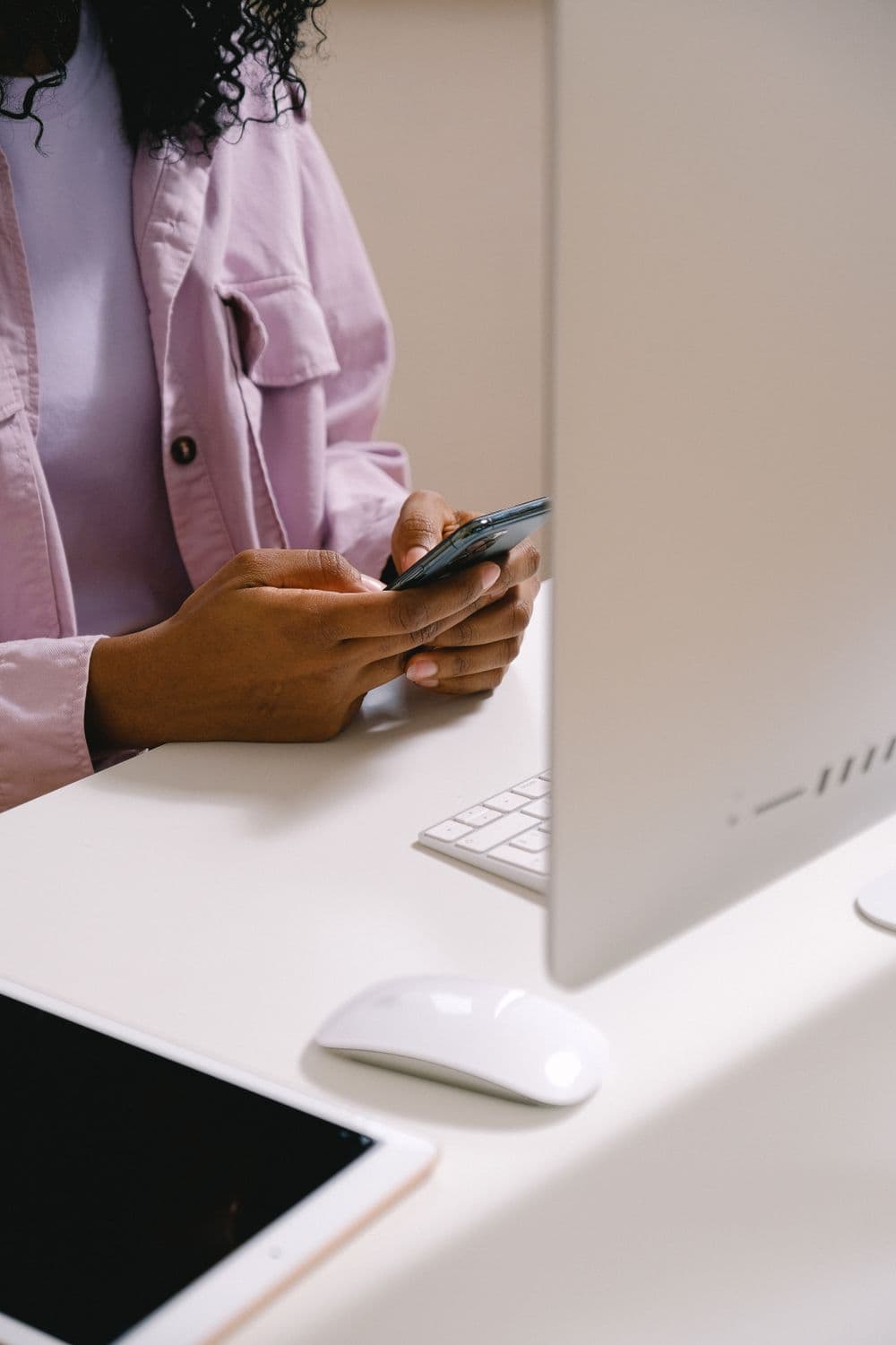 Someone answering customer messages on a phone beside a computer